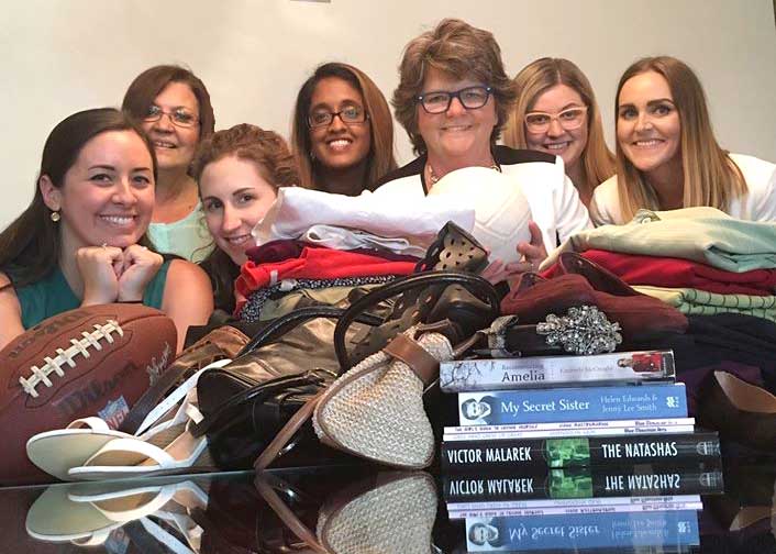 Seven Lashbrook employees posing for a photo in the Lashbrook boardroom with multiple donations for Goodwill Industries.