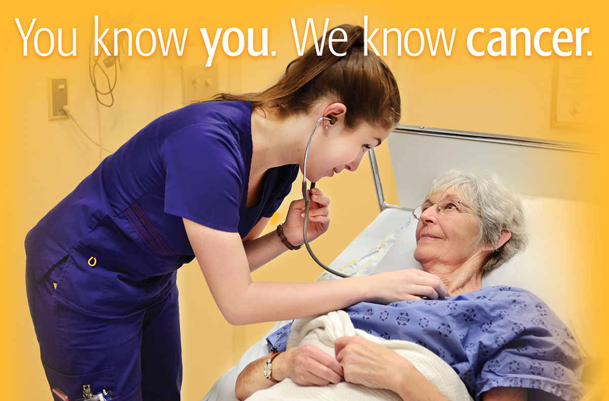 Female nurse listening to female patient’s heart rate at the beside, as part of a cancer program poster. 