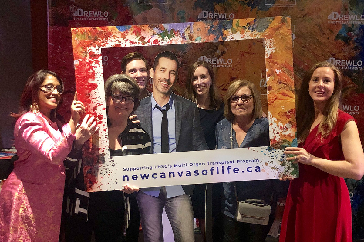 Lashbrook team posing with cardboard cutout and New Canvas of Life frame.