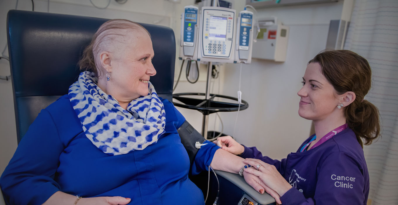 Female cancer patient and female nurse looking at each other during treatment.