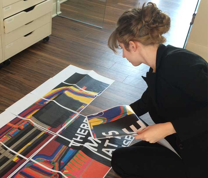 Graphic designer, Sarah Ross, putting papers together on the floor in the creative agency studio.