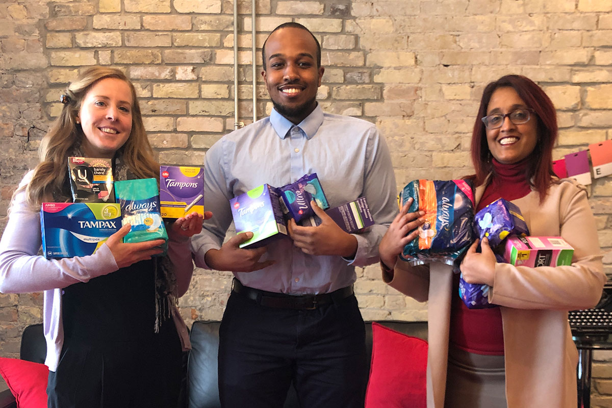 Lashbrook team holding a plethora of tampons and feminine hygiene products. 